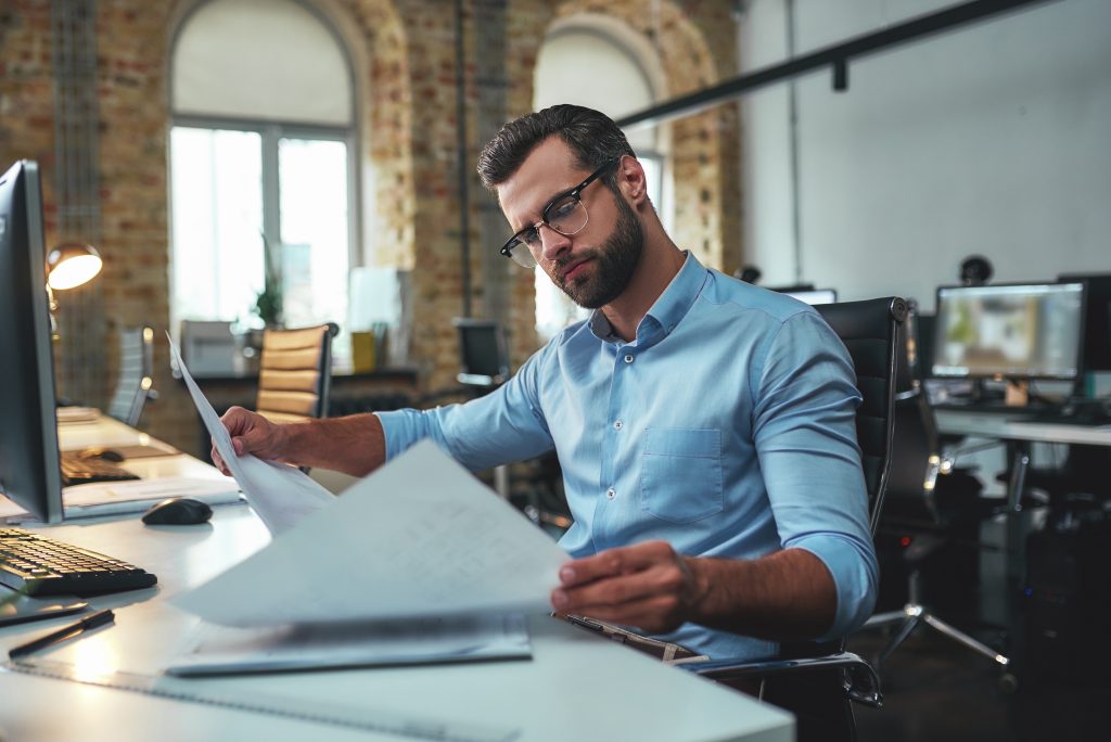 Business professional reviewing project plans at a desk.