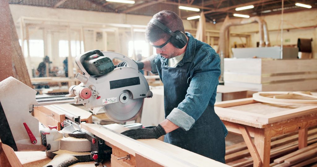 Carpenter working with a miter saw in a workshop.